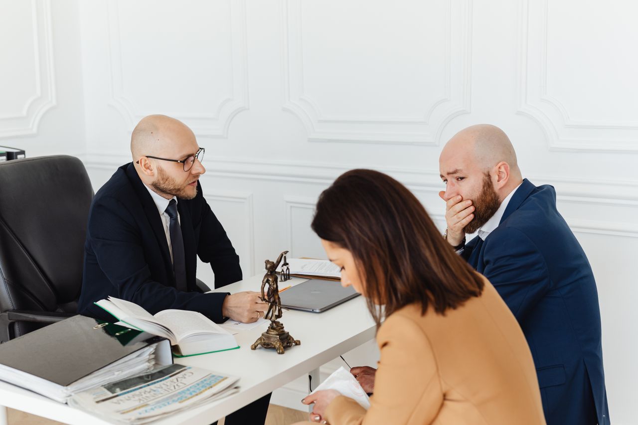 A serious legal consultation in a professional office environment involving three adults.