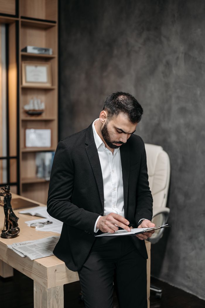 services-img Focused male in suit reviewing paperwork in modern office setting.